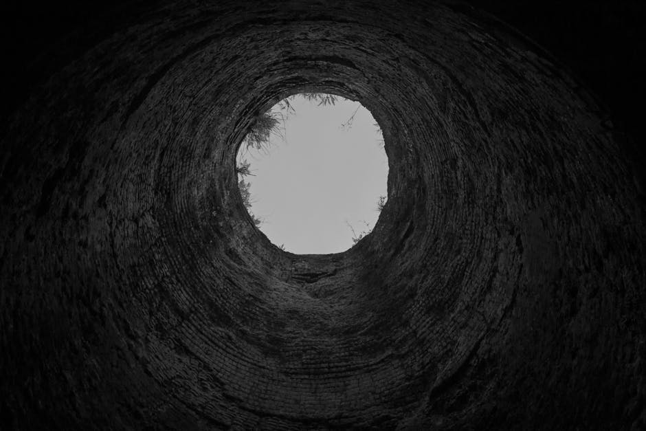 Black and white photograph looking upward from inside a well shaft.